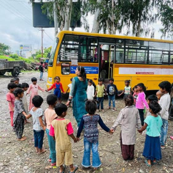 An Aasraa Trust teacher conducts a Social and Emotional Learning group activity with children outside the Mobile Learning Centre bus in Dehradun, encouraging teamwork and communication skills as part of the ASED-supported holistic education program.